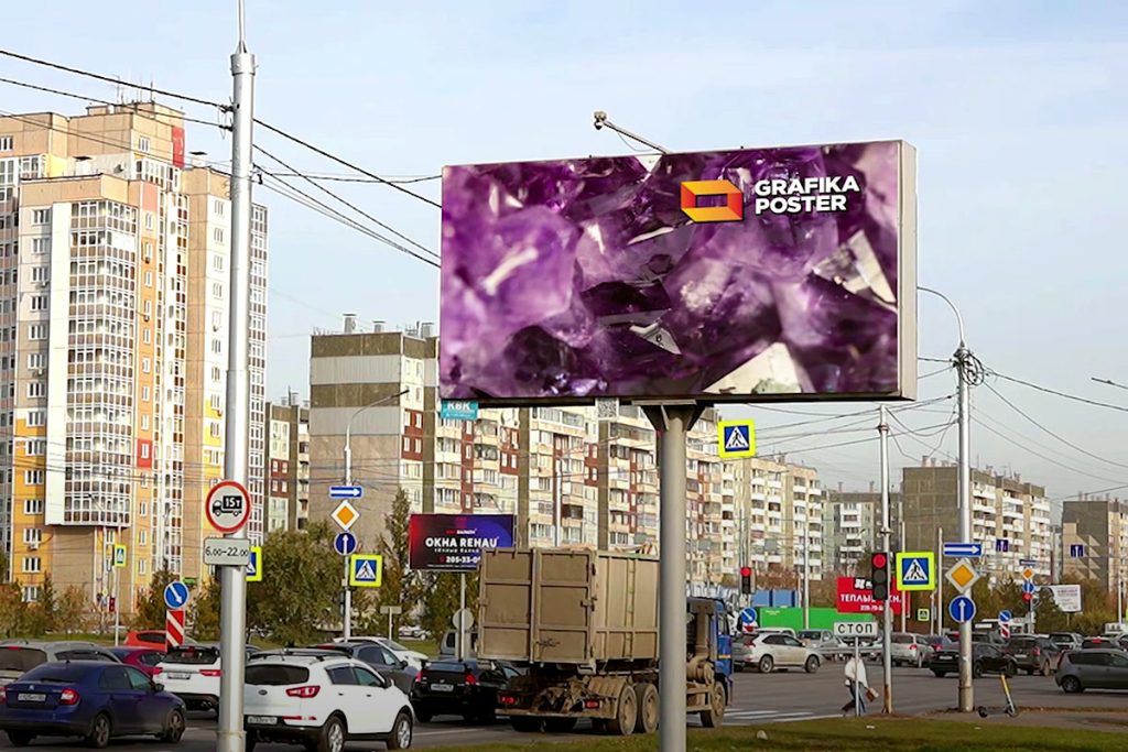 Цифровой билборд «Графика Постер» на улице 9 Мая, 77 напротив ТРК «Планета» в Красноярске, днём, поток машин